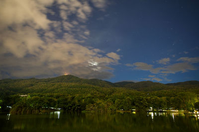 Scenic view of lake and mountains against sky at night