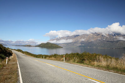 Road by lake against blue sky