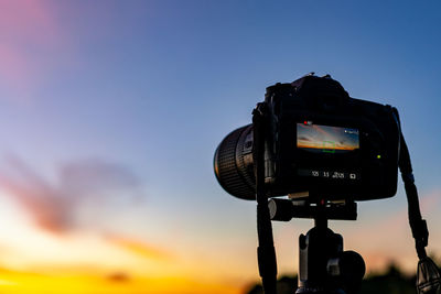 Low angle view of camera against sky during sunset