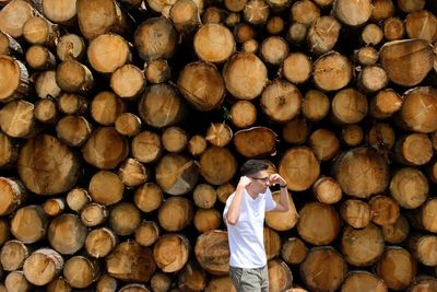 Man standing against logs