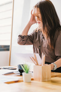 Midsection of woman looking down while sitting on table