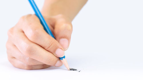 Close-up of woman hand holding pencils against white background