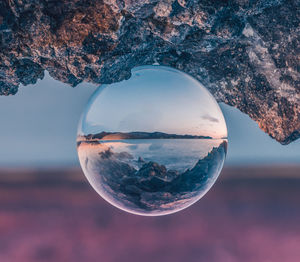 Close-up of crystal ball against sky