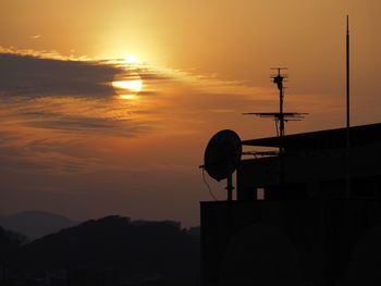 Silhouette of communications tower against sky during sunset