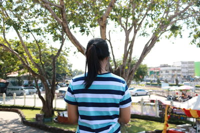 Rear view of woman standing against trees