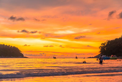 Silhouette people on beach against sky during sunset