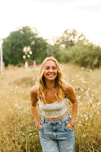 Portrait of a smiling young woman standing on field