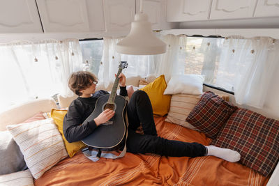 Young woman using laptop while sitting on bed at home