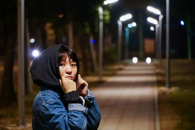 Portrait of boy standing against illuminated lights at night