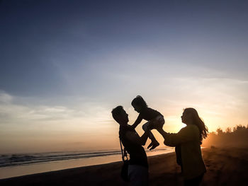 Silhouette man standing on beach against sky during sunset