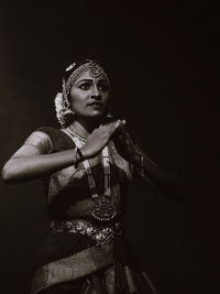 Low angle view of woman standing against black background