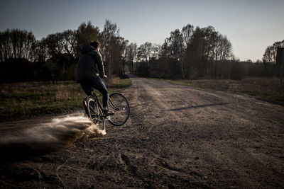 Man riding bicycle on dirt road