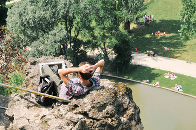 High angle view of man reclining on rock formation at park