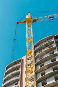 Low angle view of crane against blue sky