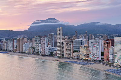 Buildings by sea against sky during sunset