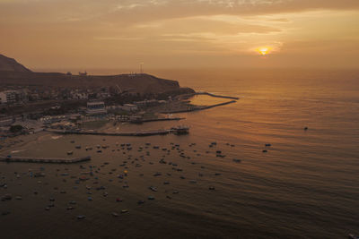 High angle view of sea and buildings against sky during sunset