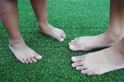 Low section of people standing green grass