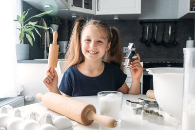 Portrait of smiling girl holding table at home