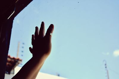 Low angle view of cropped hand against clear sky