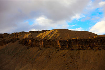 Rocky cliffs in desert against sky