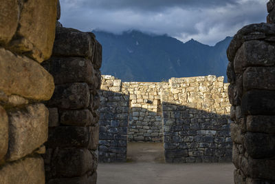 Stone wall of historic building against cloudy sky