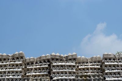 Low angle view of egg in stacked cartons against sky