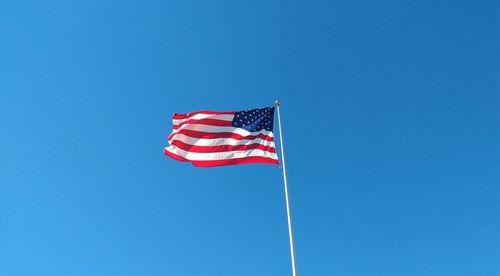 Low angle view of flag against clear blue sky