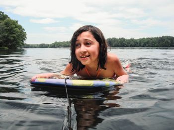 Portrait of smiling young woman holding lake against sky