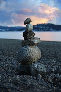 Stack of stones on beach against sky during sunset