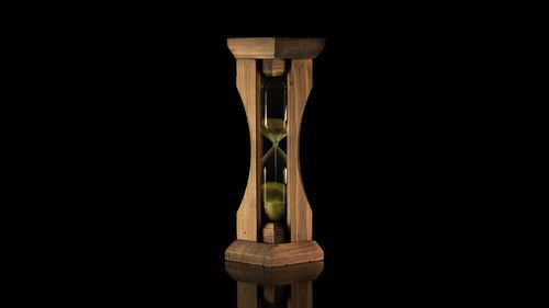 Close-up of clock on table against black background