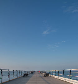 Pier over sea against clear blue sky