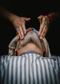 Close-up of man lying down on hand against black background