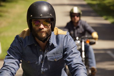 Man with friend riding motorcycles on road