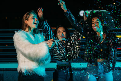 Cheerful women enjoying while standing outdoors at night