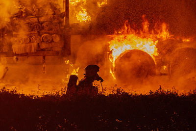 Silhouette firefighter against fire at night