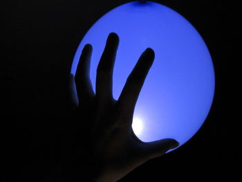 Close-up of silhouette hand against blue background