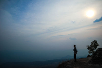 Side view of silhouette man standing on mountain against sky