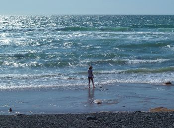 Full length of woman standing on beach against sky