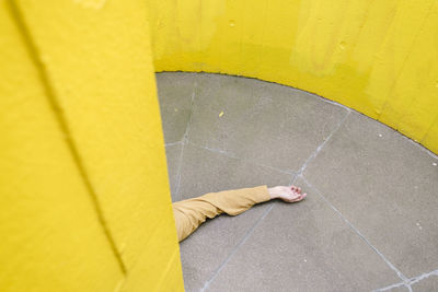 Hand of unconscious man on floor by yellow wall