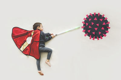 Side view of boy holding umbrella against white background