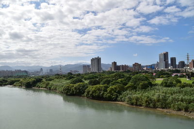 Scenic view of river by buildings against sky