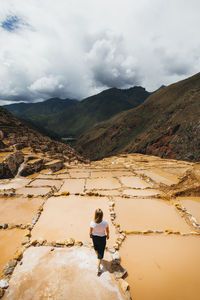 Young woman is standing near the famous salt mines in peru