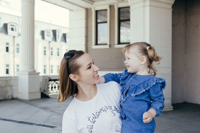 Mother and girl standing in front of building