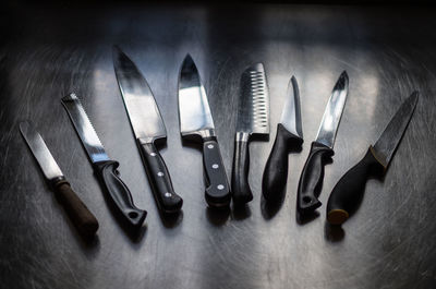 High angle view of various knives on metallic table