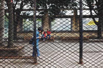 People in park seen through metal fence