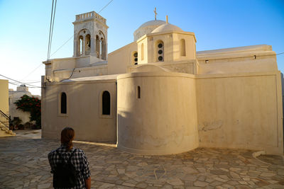 Rear view of man outside temple against building