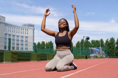 African american female athlete feels happy after running long distance on track at sports ground