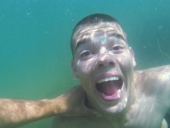 Cropped hand holding man neck swimming in sea