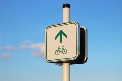 Low angle view of road sign against clear blue sky