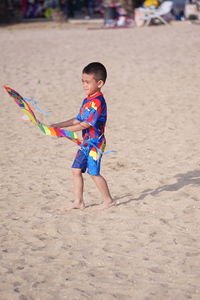 Full length of cute boy playing on sand at beach